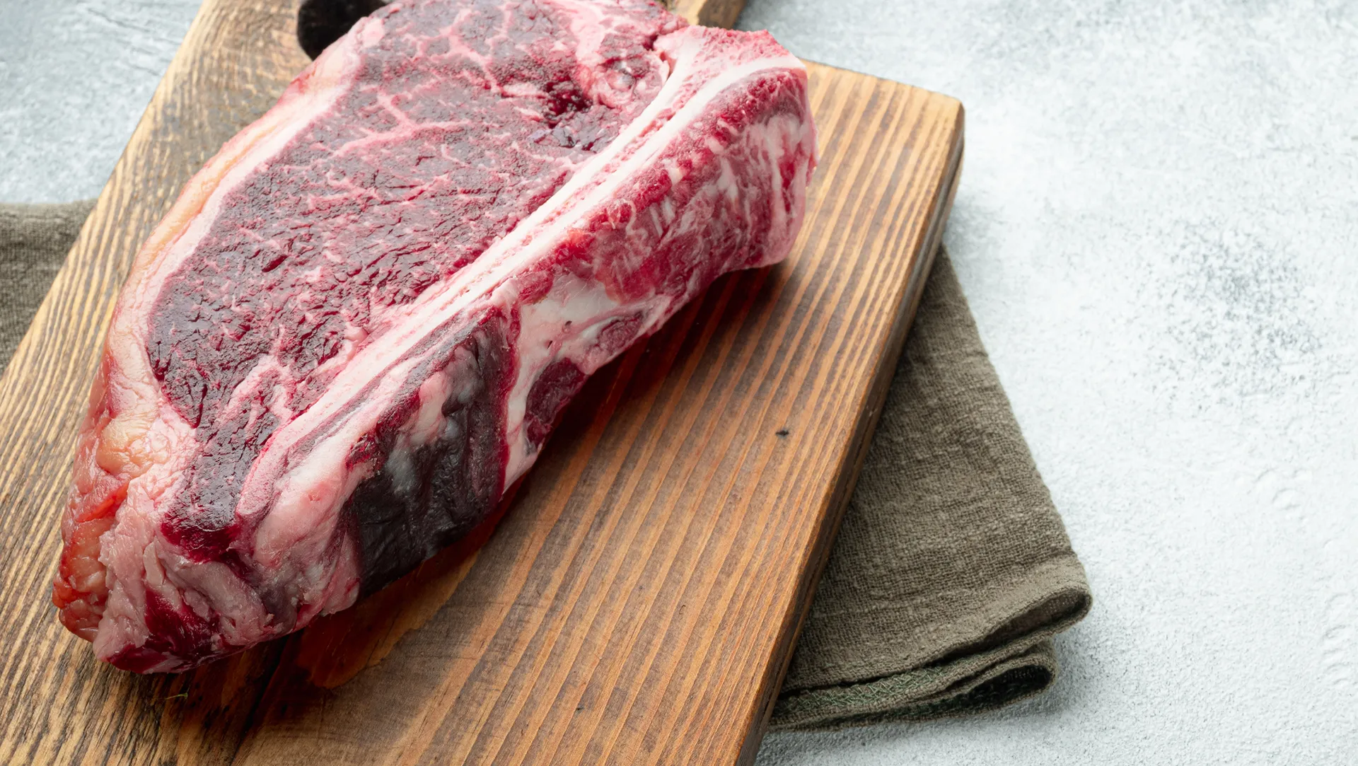 Gros plan sur une côte de viande crue sur une planche en bois.