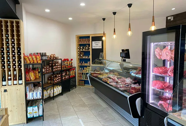 Intérieur d'une boutique avec rayons de produits et comptoir réfrigéré.