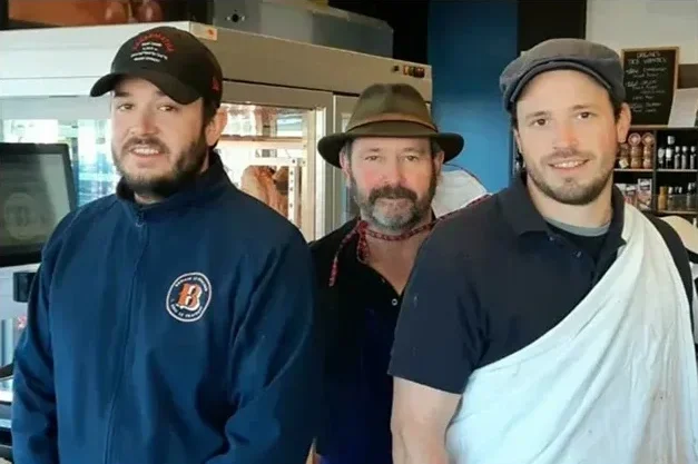 Photo de trois hommes portant des vêtements de travail et souriants.
