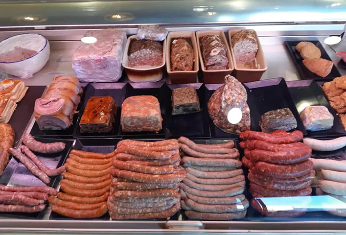 Étalage de saucisses et pâtés dans une vitrine réfrigérée.