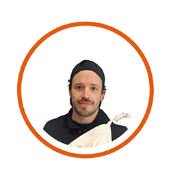 Portrait d'un homme portant une toque noire et un tablier, souriant.